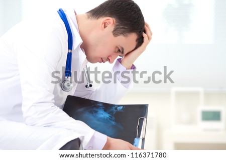 male doctor sitting and experiencing failure with X-ray snapshot of a patient