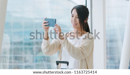 Woman taking photo on cellphone in airport