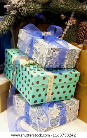 Gift boxes under the tree. Colorful boxes. The boxes are tied with a bright blue ribbon. Blue box with polka dot pattern