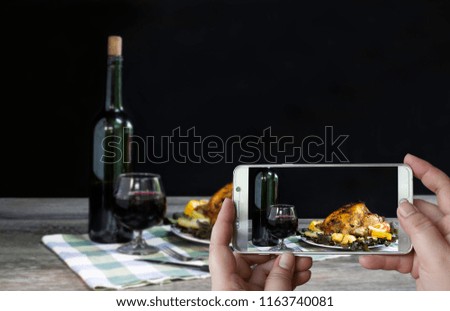 Photographing with smartphone in hand food concept with baked chicken with vegetables and grape wine which has dim light/still life and art image