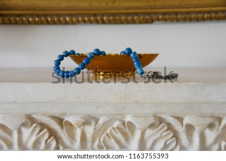 Blue islamic religion praying beads (rosary) in various  light backgrounds with different gold elements like bowl or tea serving tray. RAMADAN 