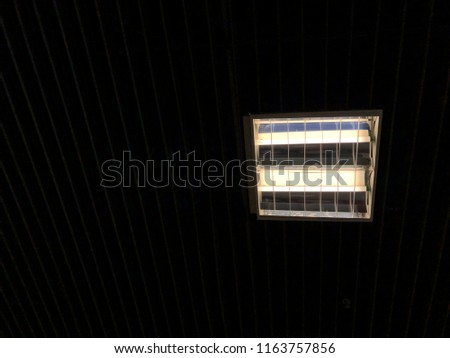 Fluorescent lamp hanging on dark ceiling, with copy space, ant's eye view, minimal design.
