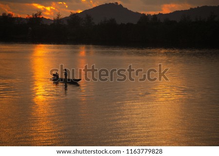 A picture of a rowing paddle in a large river in the evening, in which the sun is a beautiful yellowish orange.