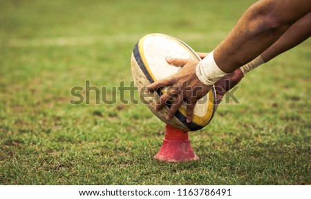 rugby player preparing to kick the oval ball during game Royalty-Free Stock Photo #1163786491