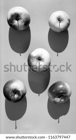 Ripe five apples on a gray background, light and shadow concept. Black and white picture from above, top view.