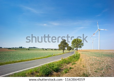 asphalt road and wind generators under blue sky in Germany