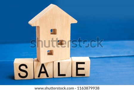 wooden house on a blue background with the inscription sale. sale of property, home, real estate. affordable housing. place for text. copy space