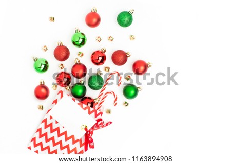 Christmas red and green balls  flowing from a gift bag on white background Flat lay, top view trendy holiday concept.