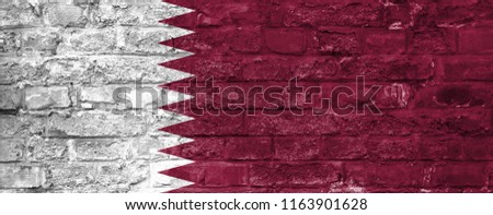 Flag of Qatar over an old brick wall background, surface.