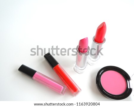 Top view and a selective focus shot of cosmetics, lipsticks and blush, on white background. The image implying concept of cosmopolitan lifestyle.