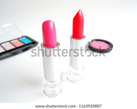 Eye level and a selective focus shot of cosmetics, lipsticks and blush, on white background. The image implying concept of cosmopolitan lifestyle.