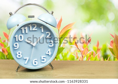alarm clock on wooden with morning colorful nature background