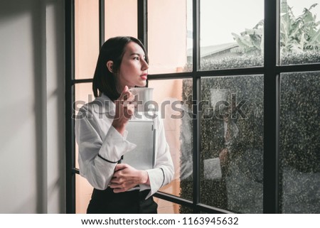 A teenager who is enjoying a cup of coffee. In hand, embrace the notebook In the morning through the window Royalty-Free Stock Photo #1163945632