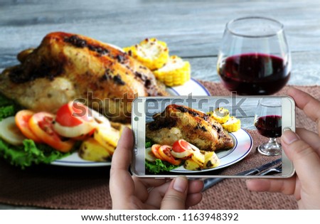 Photographing with smartphone in hand food concept with baked chicken with vegetables and grape wine which has /still life and art image