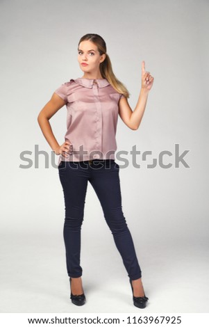 young beautiful girl in business suit, full-length, shows forefinger up, an idea appeared, isolated on background