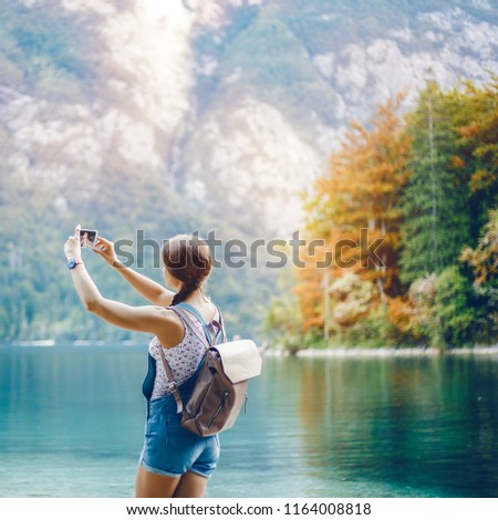 Young girl takes pictures on a smartphone. White Caucasian girl on the background of turquoise water.