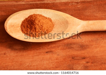 cinnamon powder in wooden spoon