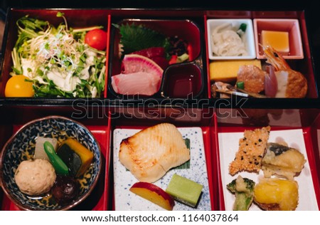 Bento box. Bento is Japanese traditional takeaway lunch box divided into small section with various food and Japanese sweet i.e. fish, tempura, potato korokke, salad & cooked vegetables