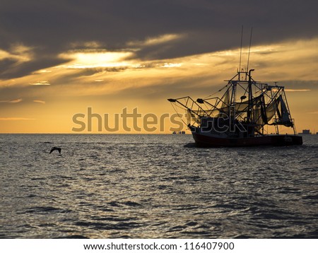 Fishing boat sailing into Gulfport Biloxi Sunset Royalty-Free Stock Photo #116407900