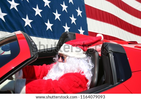 Santa Claus American Flag. Santa Claus drives his Red Hot Rod Car with an American Flag Background. American Santa.  Santa Stands for the Pledge of Allegiance. 