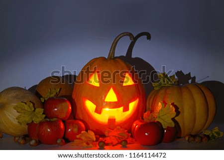 Pumpkin-head, nuts, apples and yellow leaves on a gloomy gray background. Halloween is a fun holiday.