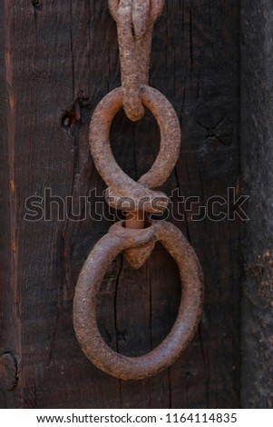 double ring at end of rusty wrought iron chain wooden background