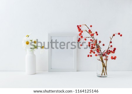 Mockup white frame and branches with small red apples in a vase on a light background