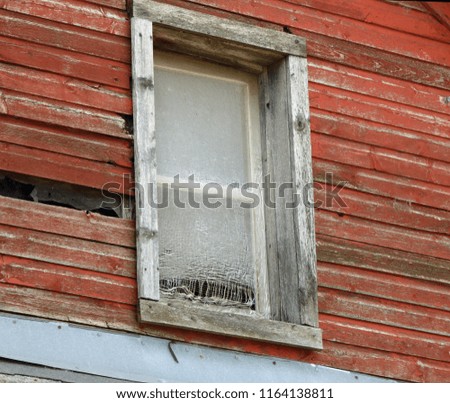 Detail of window with shredded screen in an old barn