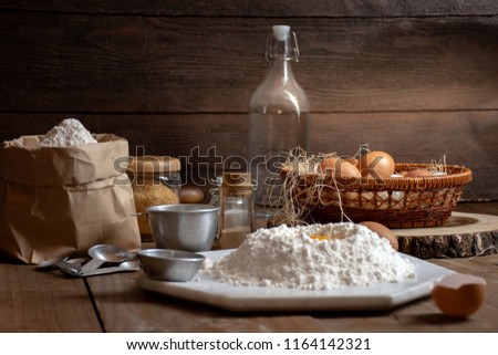 Eggs, dough and flour on wooden table with splat background for an object in a bakery