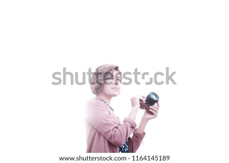 A girl on a white light background with a mirrorless in her hands looks aside to empty space