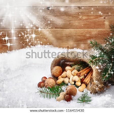 Festive christmas nuts and spices tumbling from a burlap bag onto fresh winter snow with sunlight catching twinkling falling snowflakes and copysapce