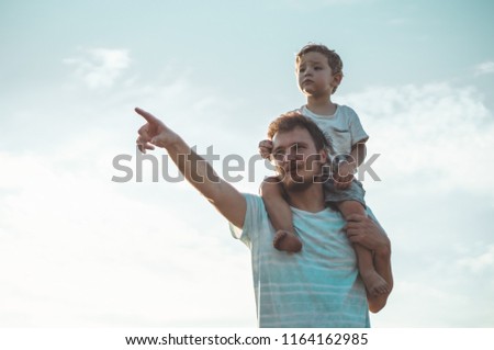 Happy kid playing with father. Dad and son outdoors. Father carrying child on his back. Happy family in summer field. 