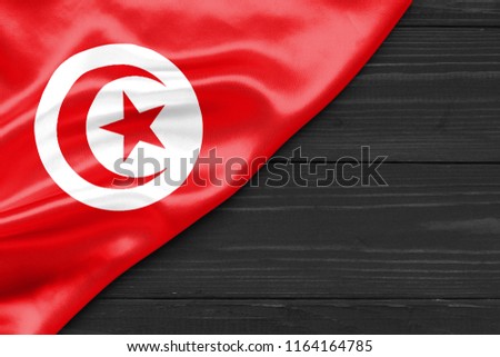 Flag of Tunisia and place for text on a dark wooden background