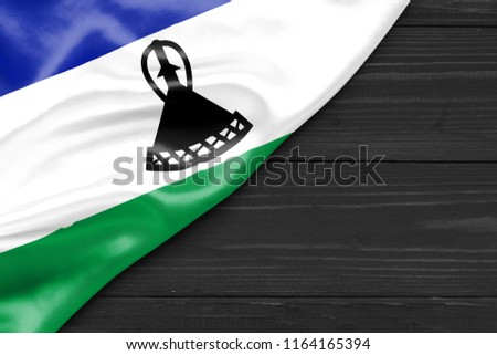 Flag of Lesotho and place for text on a dark wooden background