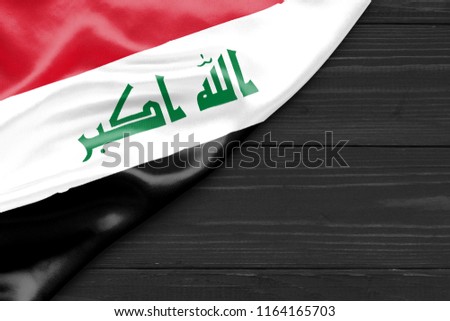 Flag of Iraq and place for text on a dark wooden background
