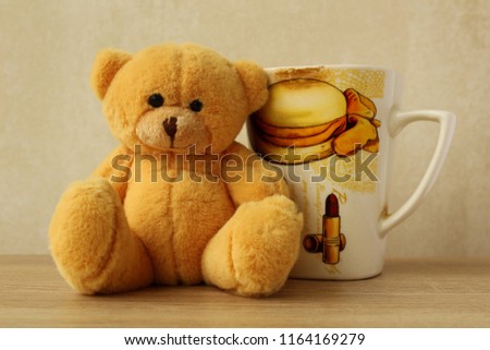 Interesting picture: little plush teddy bear with fashion cup of aromatic coffee. Good present for girl. Cool background for magazine and instagram. 