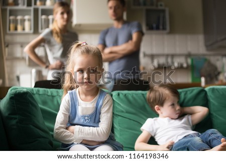 Frustrated kid girl feels upset, offended or bored ignoring avoiding worried parents and brother, little sad sister not talking to child boy after fight sulking sitting on couch, siblings rivalry Royalty-Free Stock Photo #1164198346