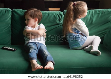 Upset siblings boy and girl sulking sitting with arms crossed on sofa not talking, kids brother sister ignoring each other after fight about tv channel choice, children conflicts and rivalry concept Royalty-Free Stock Photo #1164198352