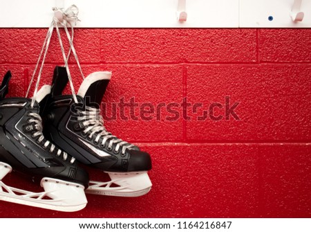 Hockey skates hanging in locker room with copy space in red background