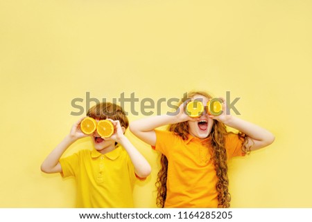 Laughing kids with orange eyes shows white healthy teeth on a yellow background. Healthy, lifestyle and a happy childhood concept. Royalty-Free Stock Photo #1164285205