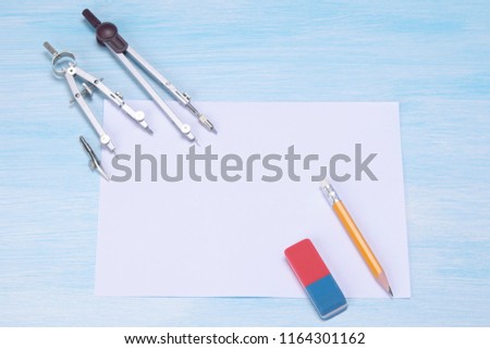 against the background of the blue table is a white sheet and a compass for drawing eraser.