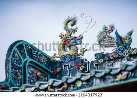 Red and golden Dragon statue with bluebird statue on the rooftop of the Chinese Temple with the clear blue sky in the background. Beautiful rooftop wall designs.
