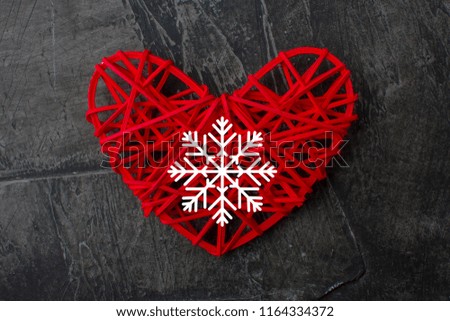 Red heart with a white snowflake on a dark background with copy space