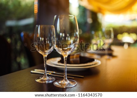 Sparkling glassware stands on long table prepared for wedding dinner.