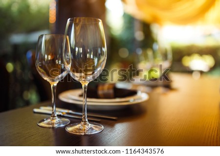 Sparkling glassware stands on long table prepared for wedding dinner.
