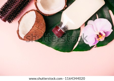 Coconut oil and halves of fresh coconut on a pink background. Hair care spa concept