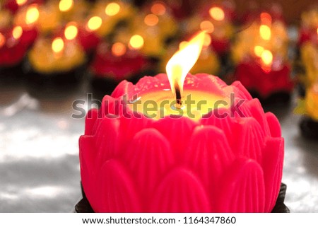Candle in front of many defocused candle flames. Flower candles burning at night. Many burning candles with shallow depth of field.
