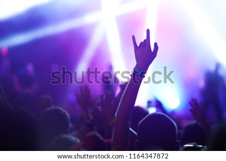 cheering crowd at a rock concert. Music fans enjoying rock concert with hand in the air. 