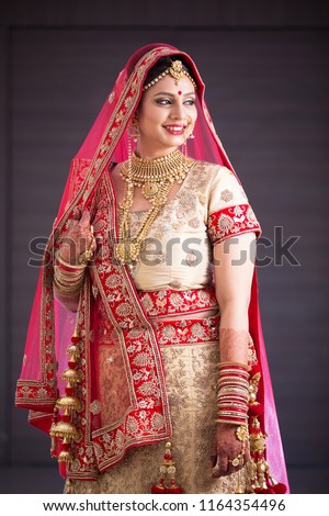 Portrait of  happy indian woman wearing traditional red color bridal costume with golden jewelery. Gold loan concept.  Royalty-Free Stock Photo #1164354496
