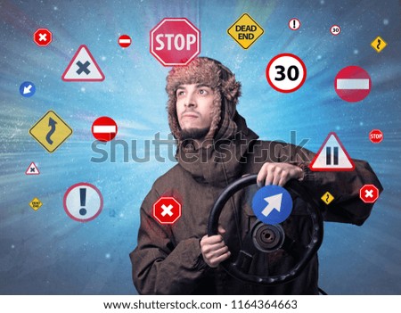 Young man holding black steering wheel with road signs surrounding him